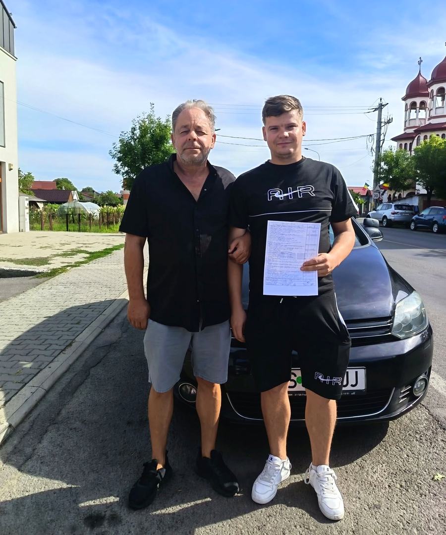 Instructorul auto Alexandru Salati cu un cursant admis, lângă mașina școlii, în Reghin
