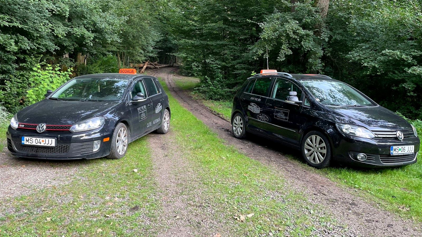 Cele două mașini ale școlii: un VW Golf cu cutie automată și un VW Golf Plus cu cutie manuală, cu tăblițele ȘCOALĂ pe plafon